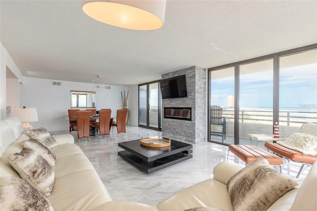 A living and dining room features marble floors, a stone fireplace, and oceanfront balcony views — 1420 N ATLANTIC AVENUE UNIT 601, DAYTONA BEACH, FL