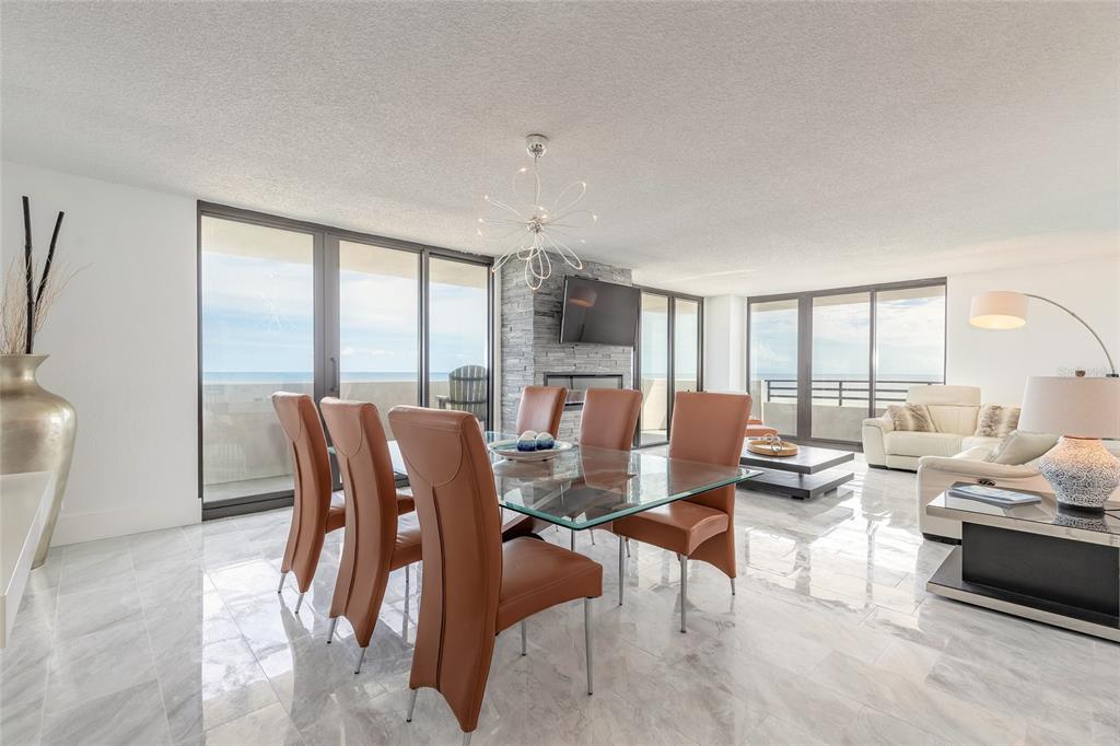 A dining area with a glass table, leather chairs, and marble floors overlooking the ocean — 1420 N ATLANTIC AVENUE UNIT 601, DAYTONA BEACH, FL