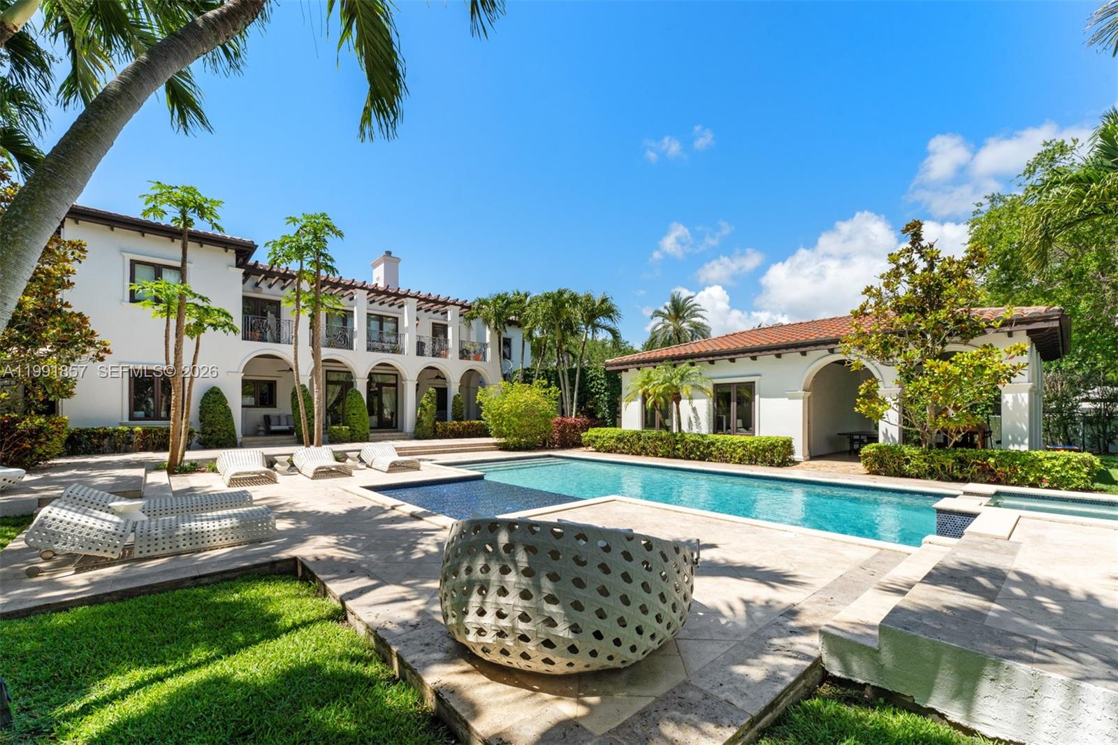 A backyard features a swimming pool, patio furniture, and a two-story white stucco house — 12575 Pine Needle Ln, Pinecrest FL 33156, PINECREST, FL