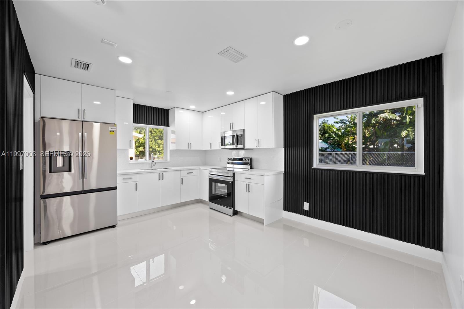 A modern kitchen features white cabinets, stainless steel appliances, and black slatted accent walls — 22503 SW 113th Pl, Miami FL 33170, MIAMI, FL