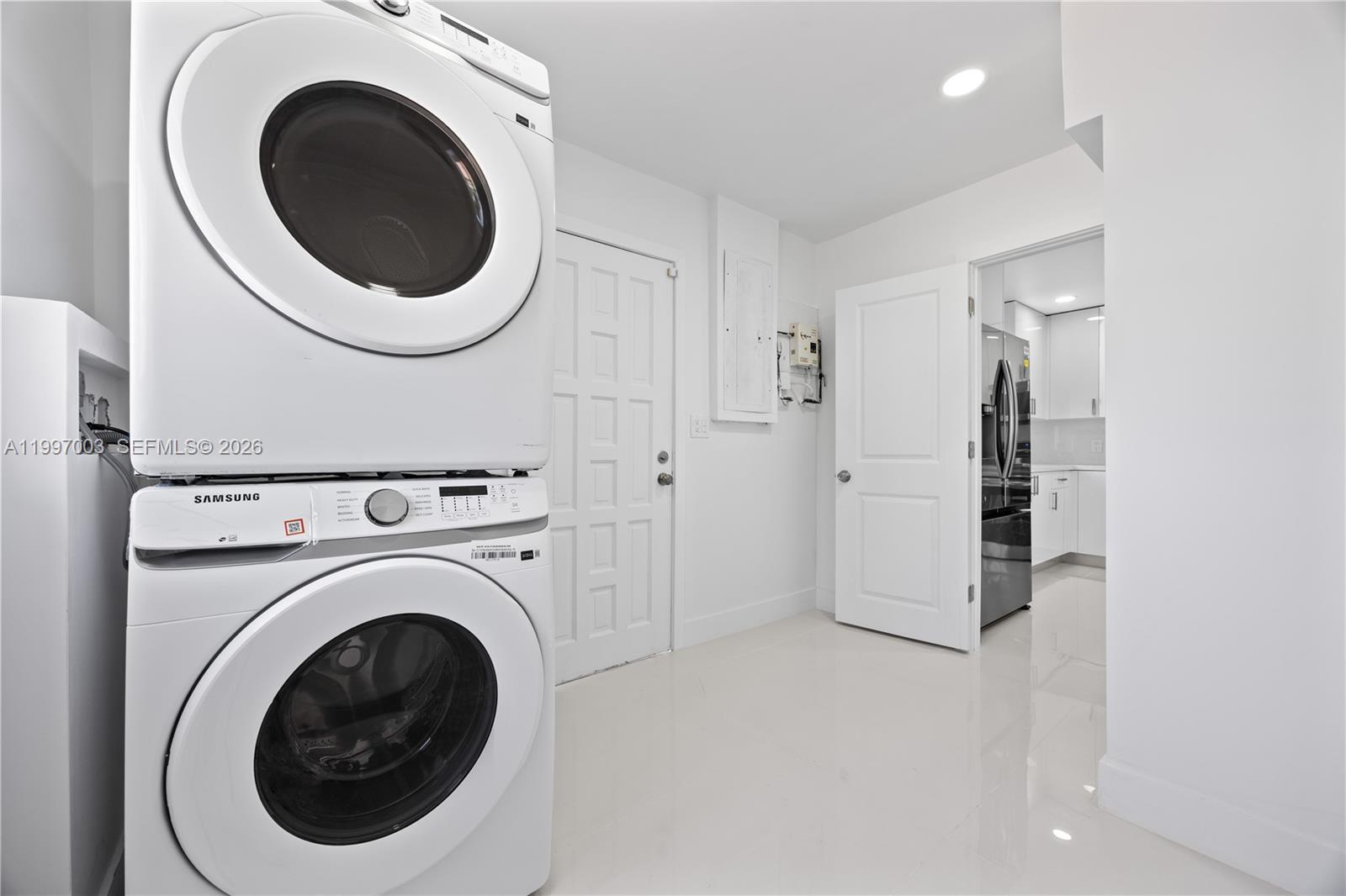 A laundry room features a stacked Samsung washer and dryer set on a white tiled floor — 22503 SW 113th Pl, Miami FL 33170, MIAMI, FL
