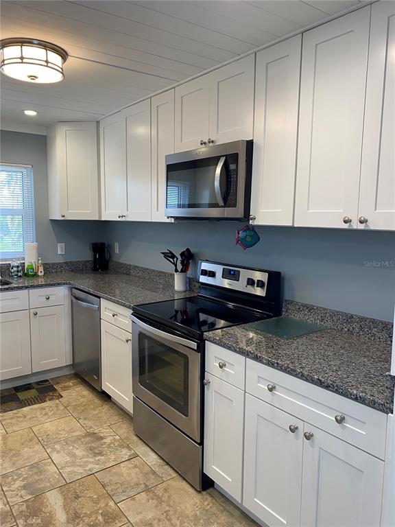 A kitchen features white cabinets, granite countertops, stainless steel appliances, and tile flooring — 10427 WATERBIRD WAY UNIT 10427, BRADENTON, FL