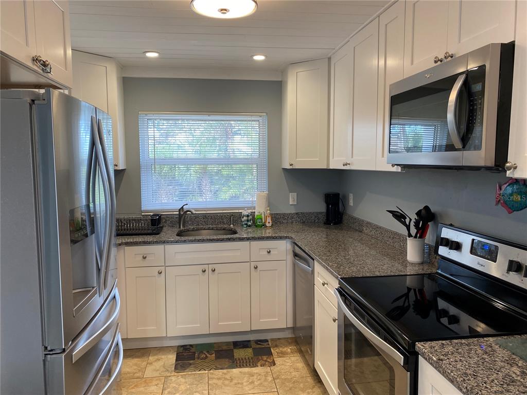 A kitchen features white cabinets, granite countertops, stainless steel appliances, and a window above the sink — 10427 WATERBIRD WAY UNIT 10427, BRADENTON, FL