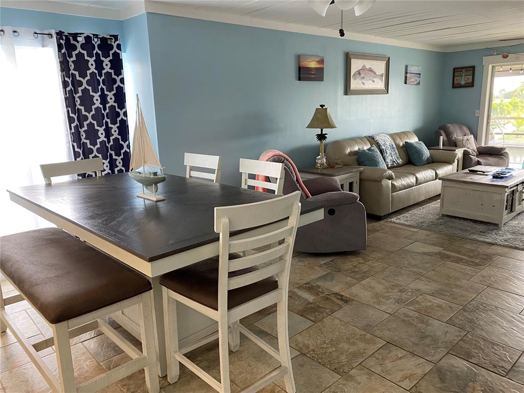A dining area with a dark wood table and chairs opens into a living room — 10427 WATERBIRD WAY UNIT 10427, BRADENTON, FL