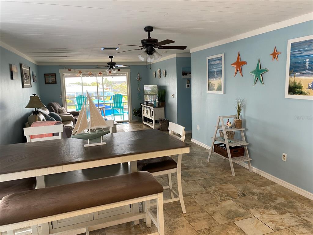 A dining area with a wooden table and bench opens into a living room with coastal decor — 10427 WATERBIRD WAY UNIT 10427, BRADENTON, FL
