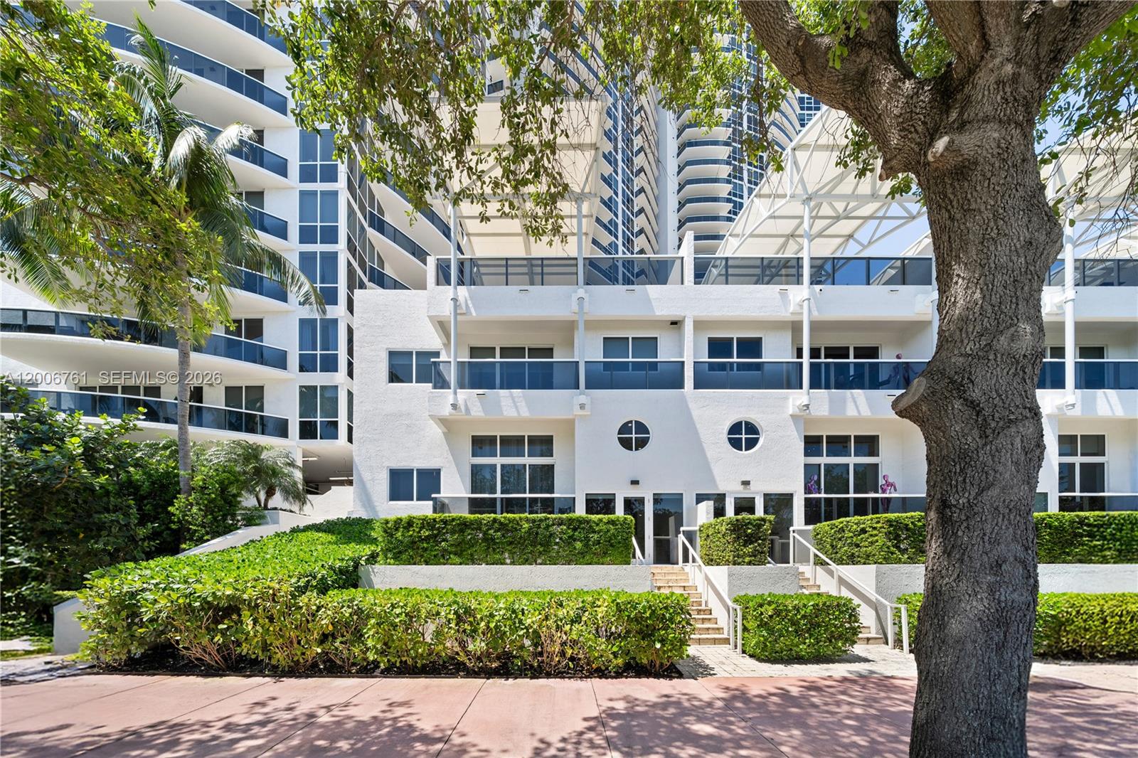 A multi-story white residential building features balconies, large windows, and a landscaped hedge exterior — 400 Alton Rd # 1A, Miami Beach FL 33139, MIAMI BEACH, FL