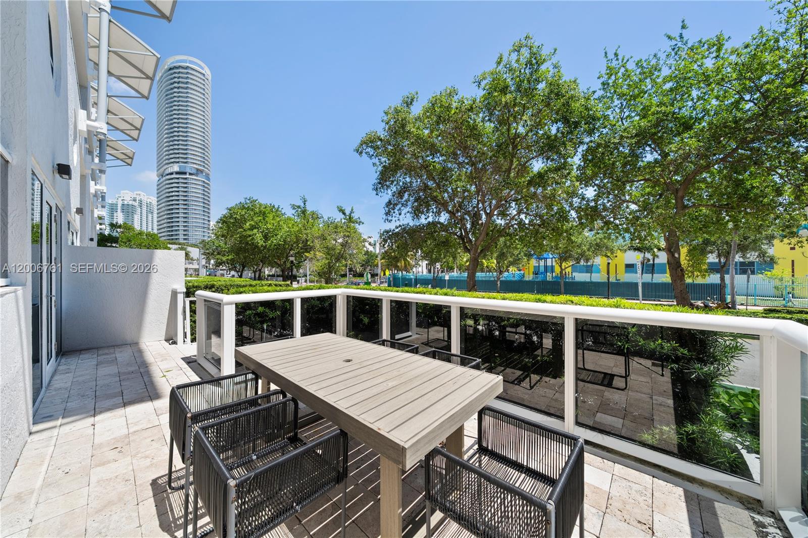 A patio features a wooden dining table with chairs, a glass railing, and city views — 400 Alton Rd # 1A, Miami Beach FL 33139, MIAMI BEACH, FL