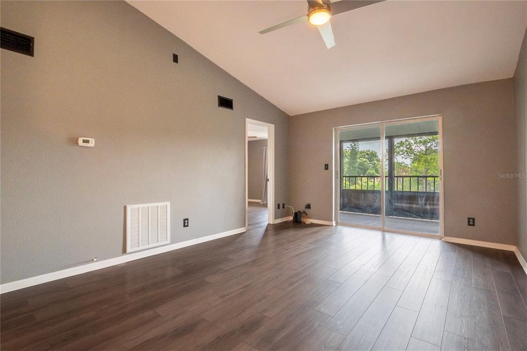 A living room with gray walls, dark wood-look flooring, a ceiling fan, and sliding doors — 11201 122ND AVENUE UNIT 234, LARGO, FL