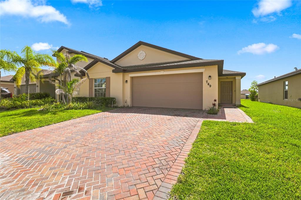 A single-story house with a brick paver driveway, two-car garage, and tan exterior siding — 749 WORLINGTON LANE, FORT PIERCE, FL