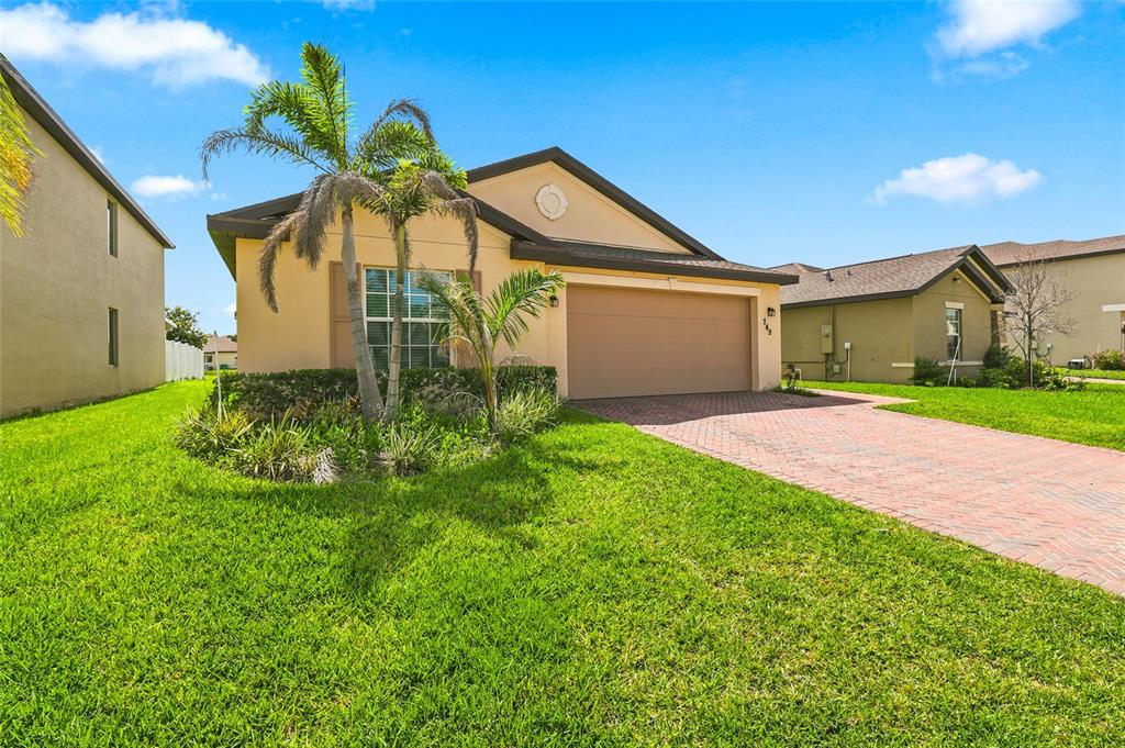 A single-story house with a tan exterior, a two-car garage, and a palm tree — 749 WORLINGTON LANE, FORT PIERCE, FL