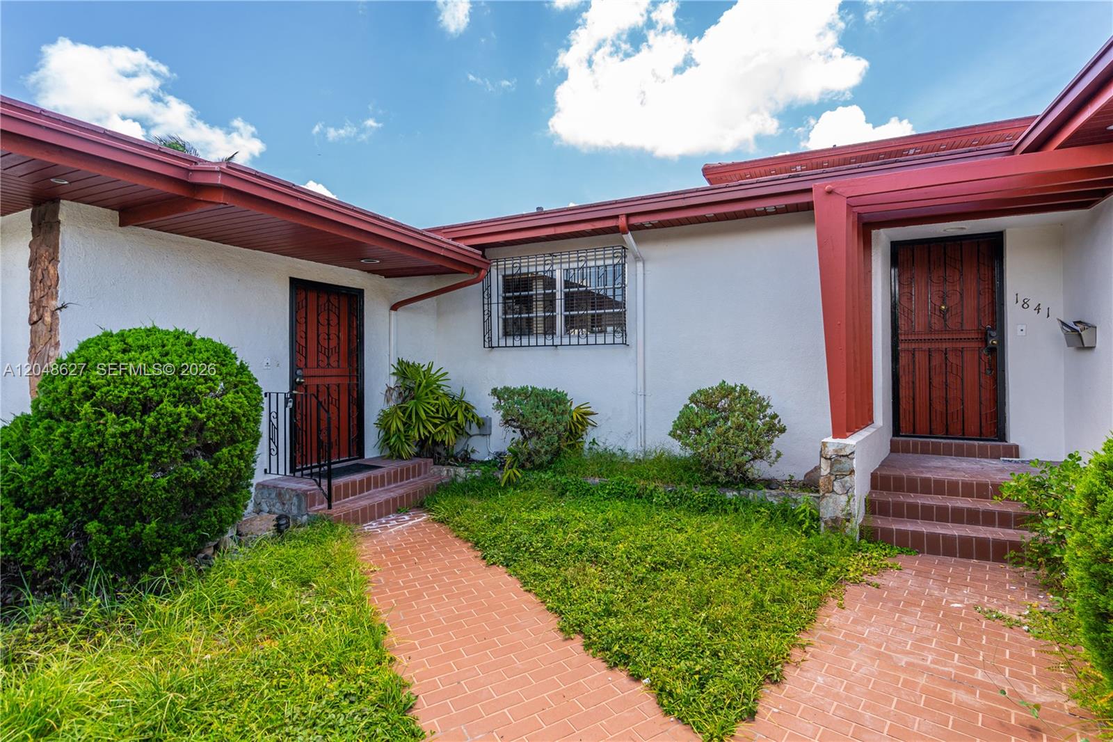 The exterior of a house features two red doors, brick walkways, and a grassy yard — 1841 SW 29th Ave # B, Miami FL 33145, MIAMI, FL