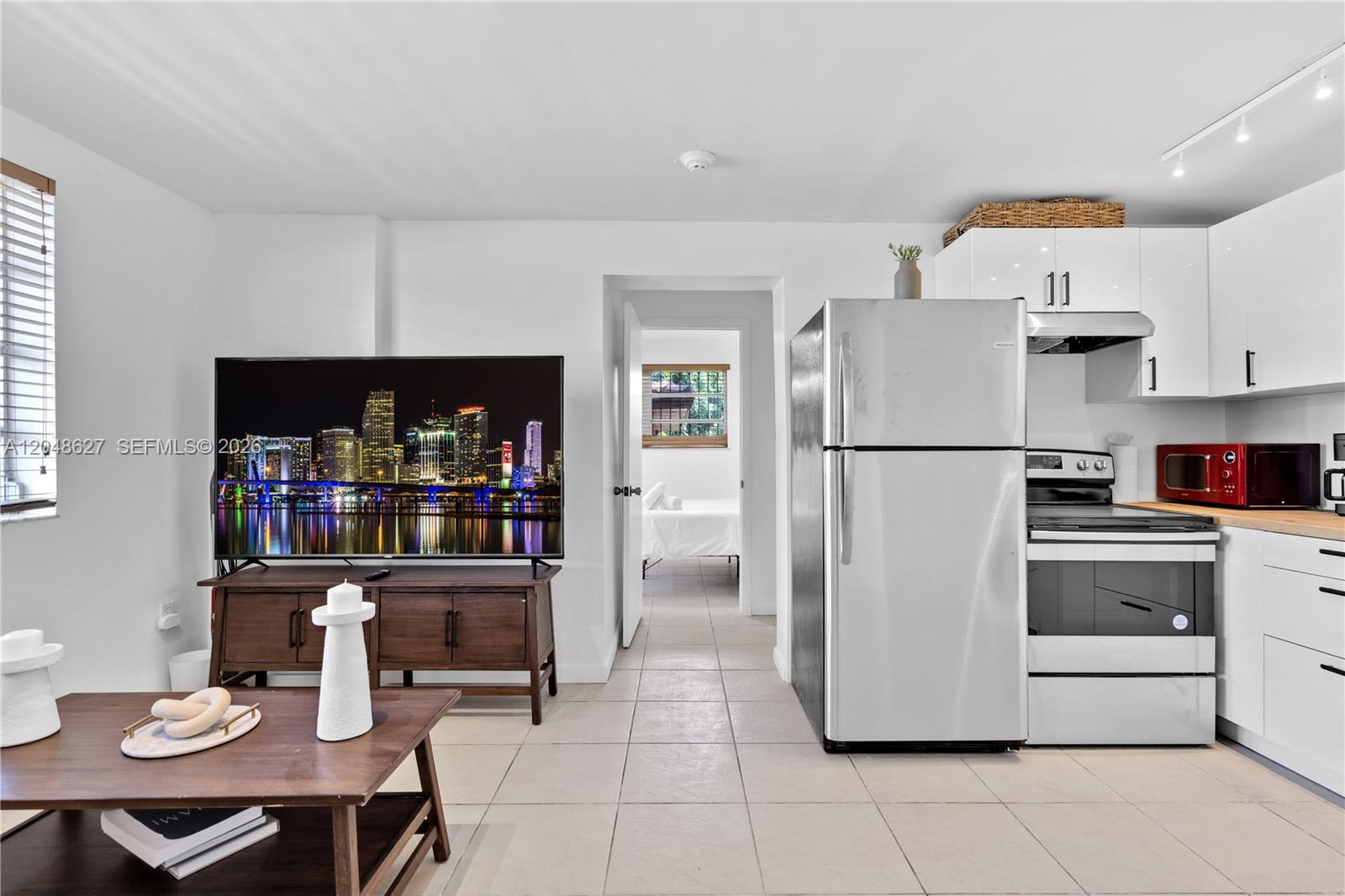 A living room and kitchen area features white cabinets, stainless steel appliances, and tile flooring — 1841 SW 29th Ave # B, Miami FL 33145, MIAMI, FL