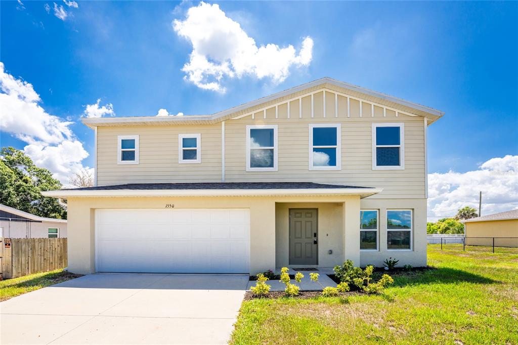 A two-story house with beige siding, a two-car garage, and a front entrance — 1550 PAXTON TERRACE, PORT CHARLOTTE, FL