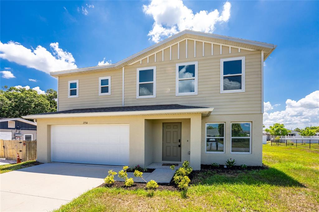 A two-story house with beige siding, a two-car garage, and a front entrance — 1550 PAXTON TERRACE, PORT CHARLOTTE, FL