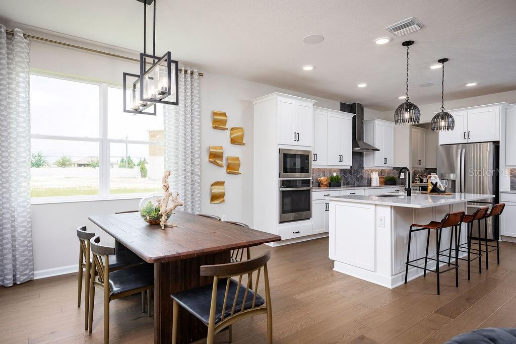 A kitchen and dining area featuring white cabinets, a wooden table, and a kitchen island — 1205 BASALT LANE, SANFORD, FL