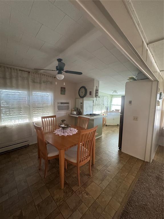 A dining area with a wooden table and chairs sits adjacent to a kitchen space — 118 52ND AVENUE W, BRADENTON, FL