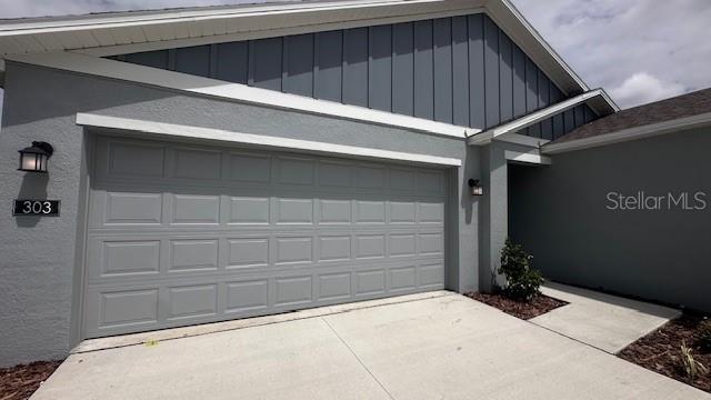 A gray house exterior features a two-car garage, a concrete driveway, and a covered entryway — 303 ARTEMIS STREET UNIT 0, LAKE WALES, FL