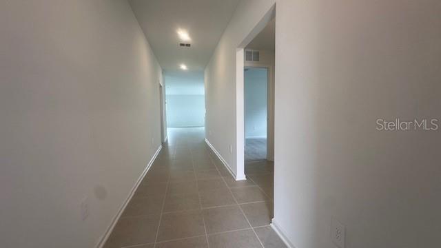 A long hallway with light-colored walls and tiled flooring leads toward an open living area — 303 ARTEMIS STREET UNIT 0, LAKE WALES, FL