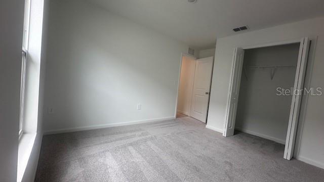 A bedroom with light gray carpet, white walls, a window, and an open closet — 303 ARTEMIS STREET UNIT 0, LAKE WALES, FL