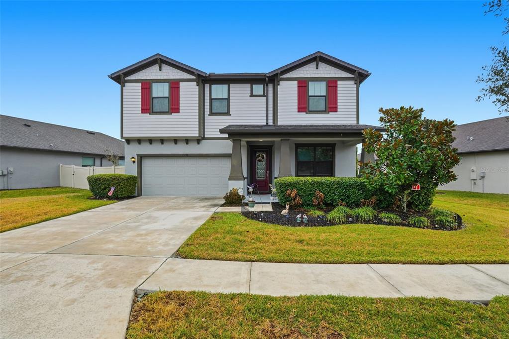 A two-story suburban house features light siding, red shutters, a garage, and a front lawn — 13338 NEWPORT SHORES DRIVE, HUDSON, FL
