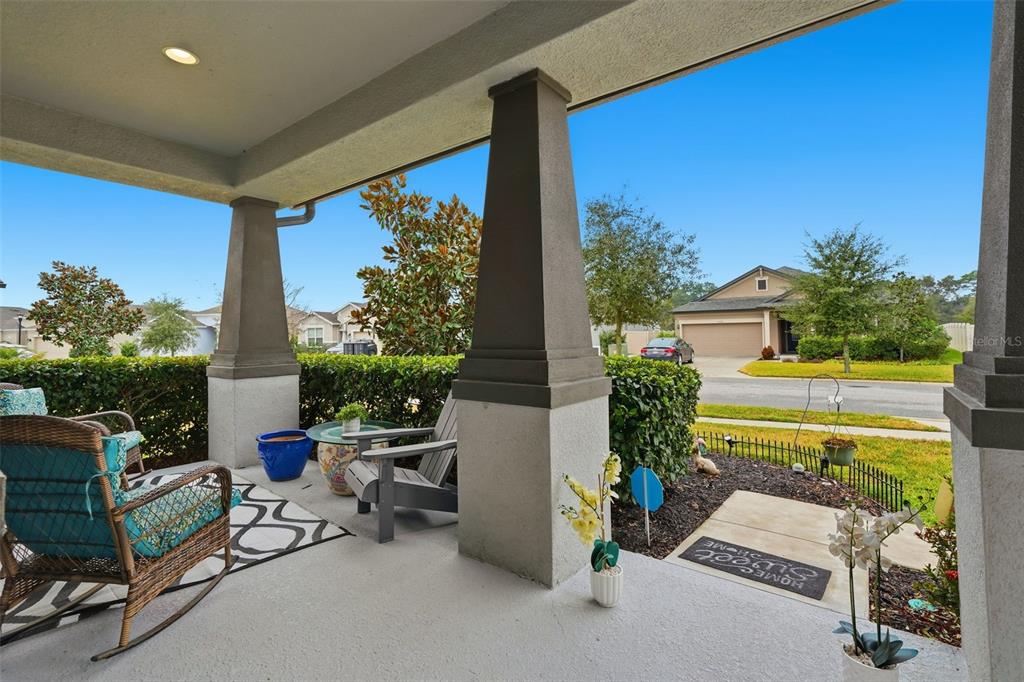 A covered front porch features concrete flooring, two large columns, and outdoor seating — 13338 NEWPORT SHORES DRIVE, HUDSON, FL