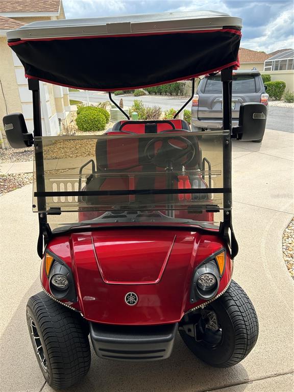 A red Yamaha golf cart is parked on a concrete driveway in front of a house — 7809 SE 171ST HARLESTON STREET, THE VILLAGES, FL
