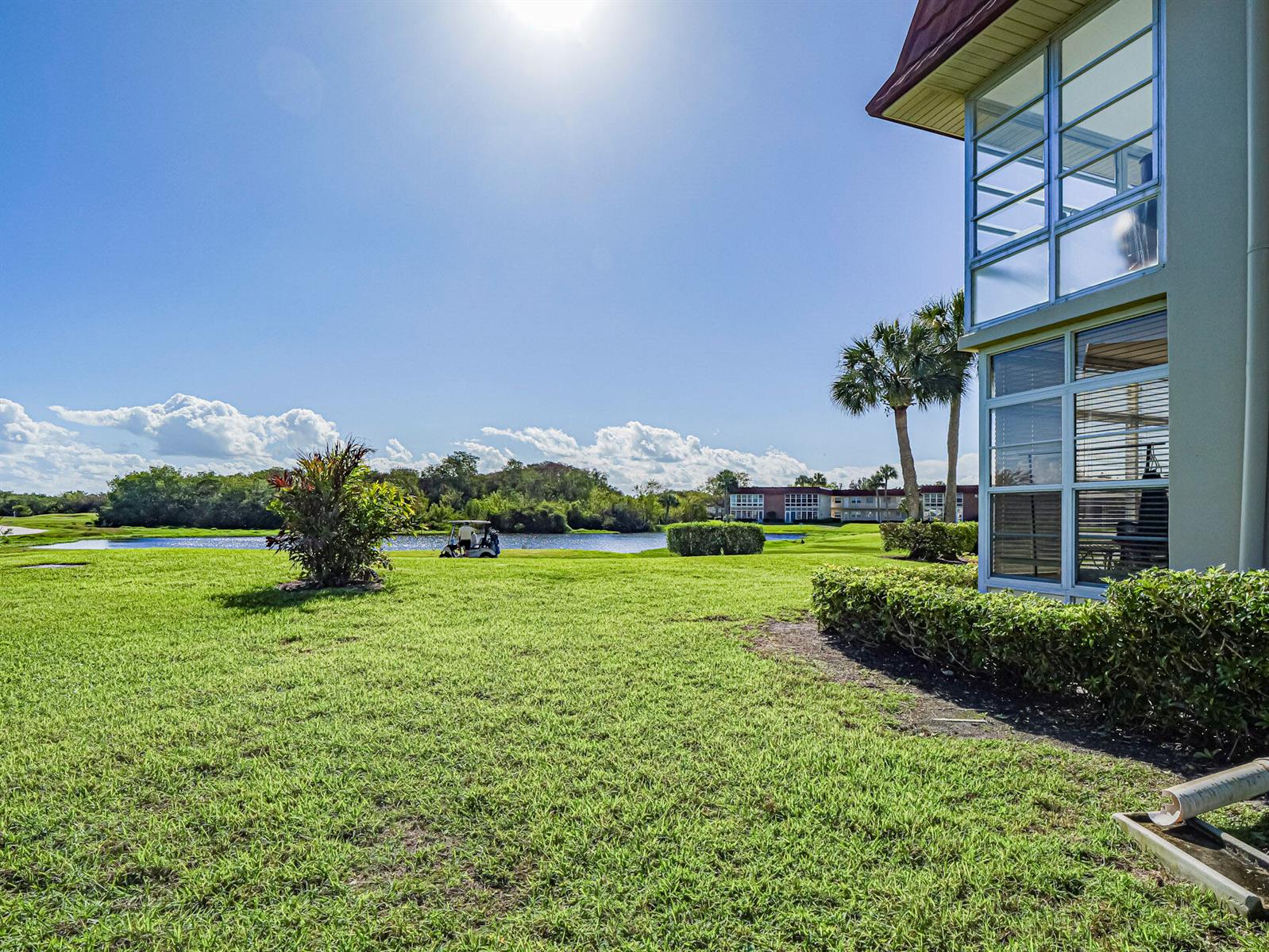A view of a grassy lawn, a pond, and a multi-story building with glass-enclosed balconies — 67 Royal Oak Drive # 206, Vero Beach FL 32962, VERO BEACH, FL