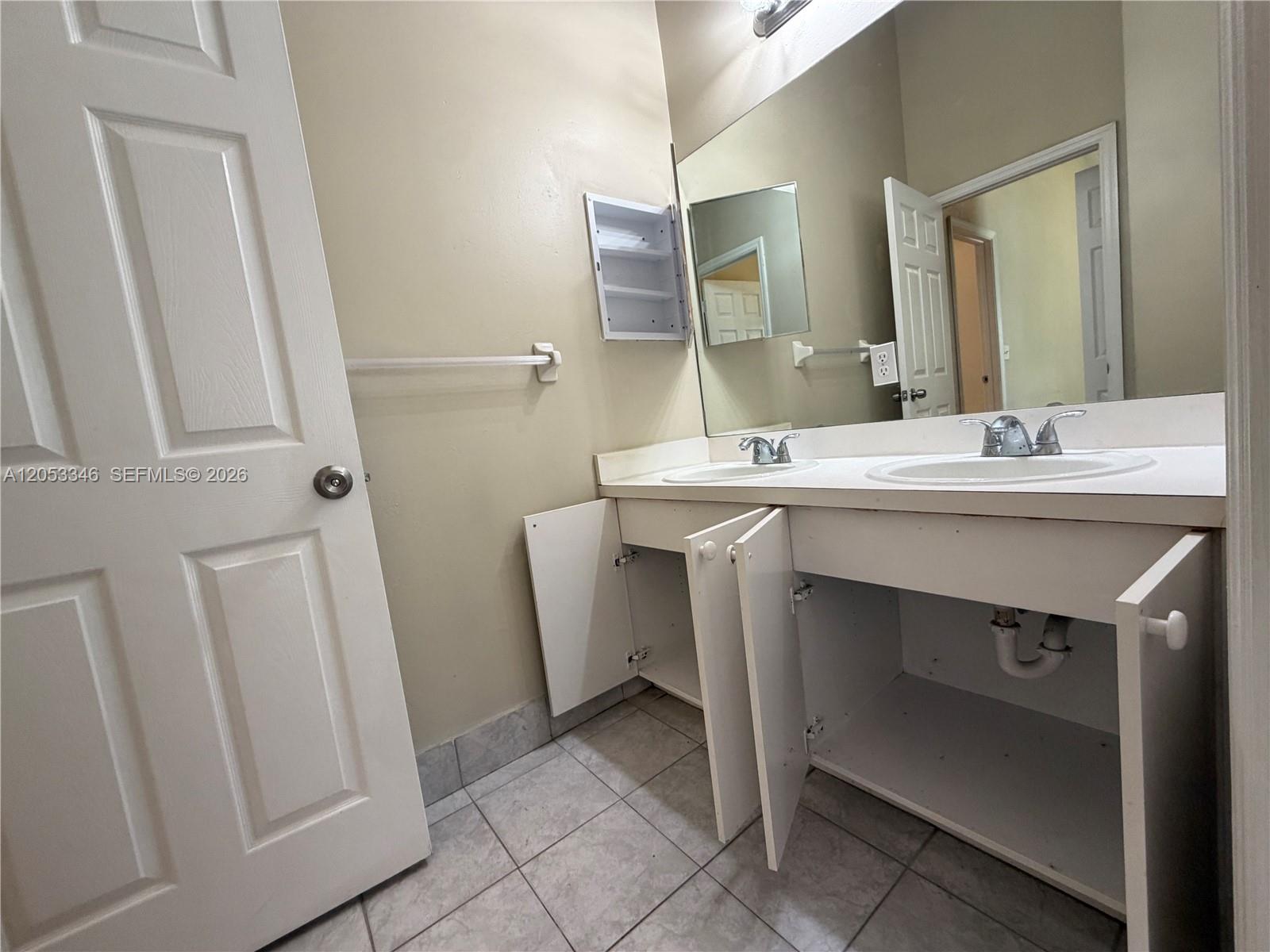 A bathroom features a double-sink vanity with open cabinets, a large mirror, and tiled flooring — 5855 Eagle Cay Ter, Coconut Creek FL 33073, COCONUT CREEK, FL