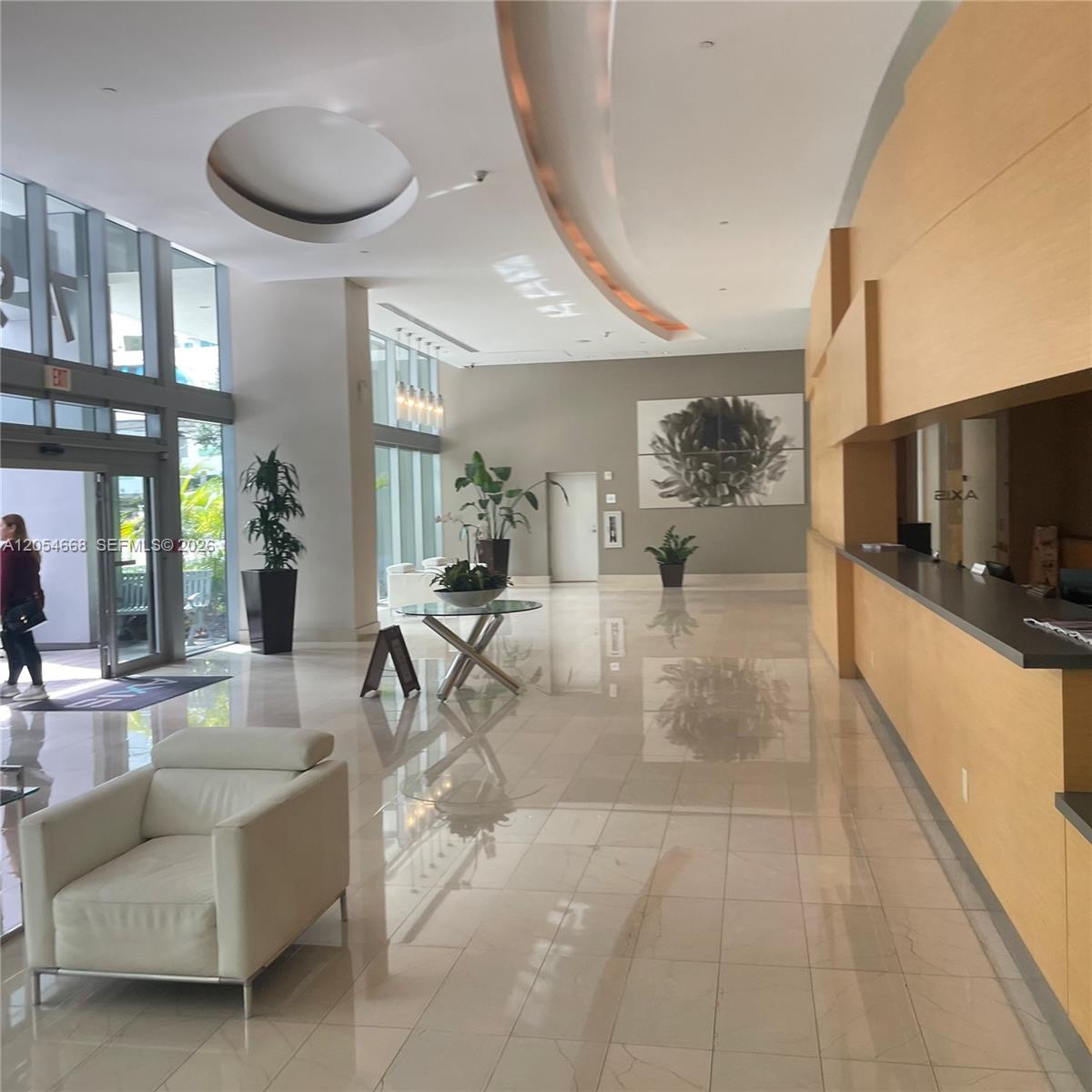 A modern building lobby features a reception desk, polished tile floors, and large glass windows — 79 SW 12 ST, Miami FL 33130, MIAMI, FL