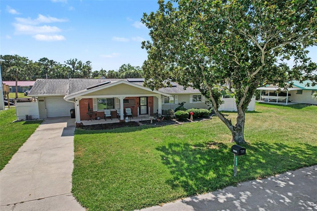 A single-story house with a brick facade, a front porch, and a large shade tree — 8639 GREEN STREET, PORT RICHEY, FL