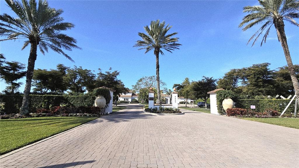 A paved driveway leads through a gated entrance flanked by palm trees and large urns — 11220 HACIENDA DEL MAR BOULEVARD UNIT 204, PLACIDA, FL