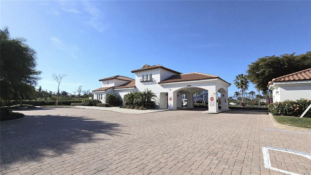 A paved driveway leads to the gated entrance of a white stucco building with tile roofs — 11220 HACIENDA DEL MAR BOULEVARD UNIT 204, PLACIDA, FL