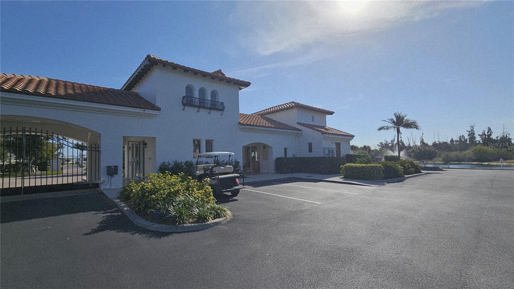 A white stucco building with a tile roof stands next to a gated entrance — 11220 HACIENDA DEL MAR BOULEVARD UNIT 204, PLACIDA, FL