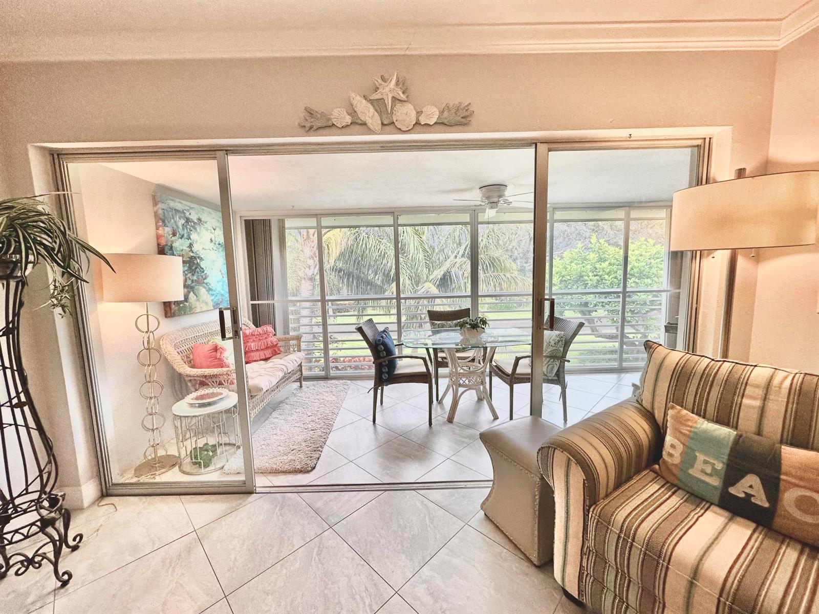 A living room with tile floors opens through sliding glass doors to a screened-in balcony — 6 GARDEN Street # 204P, Tequesta FL 33469, TEQUESTA, FL
