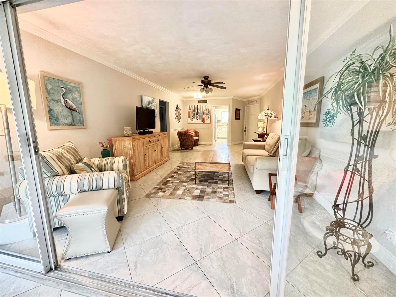 A living room with tile floors, a striped armchair, a beige sofa, and a coffee table — 6 GARDEN Street # 204P, Tequesta FL 33469, TEQUESTA, FL