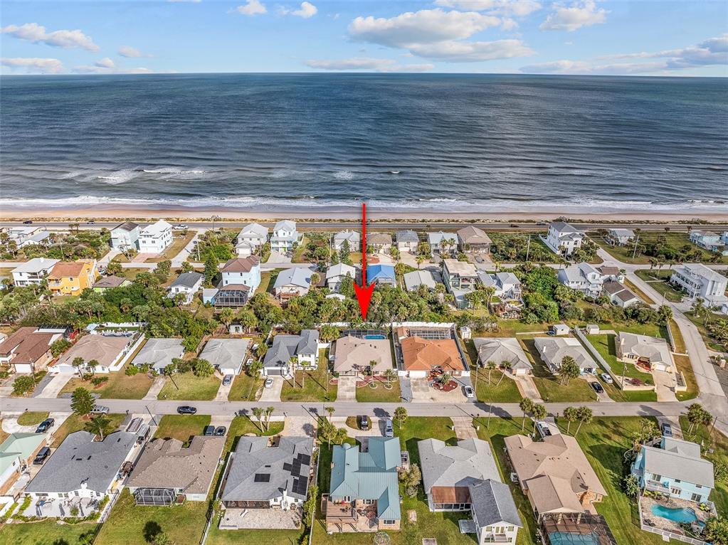 An aerial view shows a coastal neighborhood with houses, streets, and a beach — 2008 N DAYTONA AVENUE, FLAGLER BEACH, FL