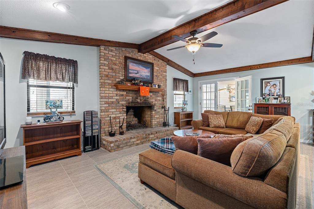 A living room features a brick fireplace, exposed wood ceiling beams, and a large sectional sofa — 2008 N DAYTONA AVENUE, FLAGLER BEACH, FL
