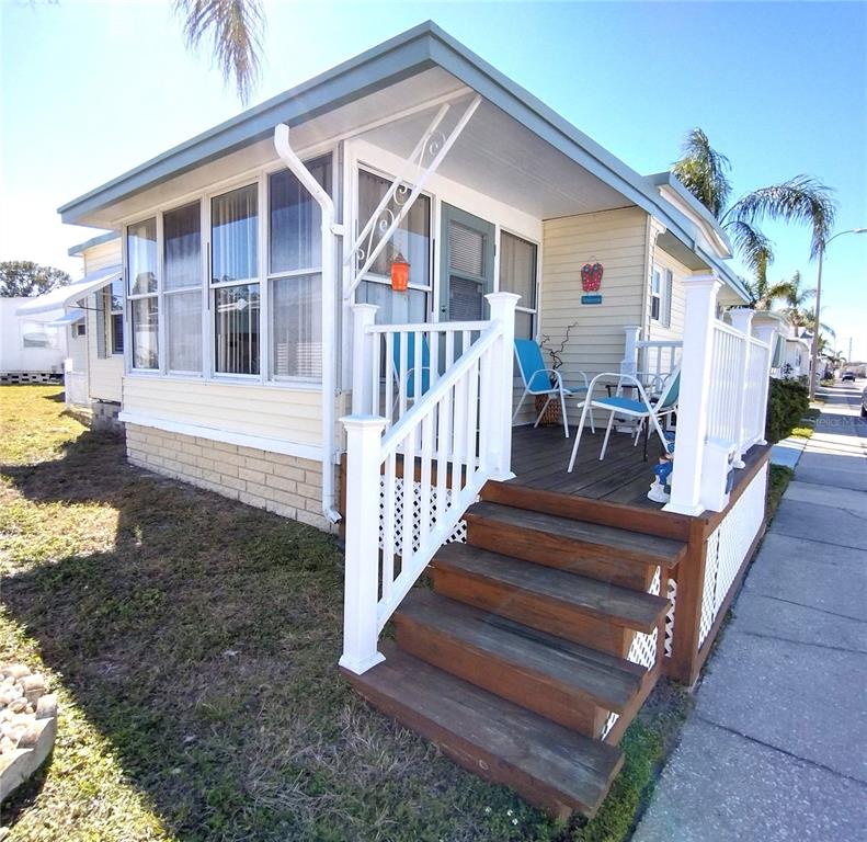 A mobile home exterior features a wooden deck with stairs and white railings — 82286 2ND AVENUE N UNIT 286, PINELLAS PARK, FL