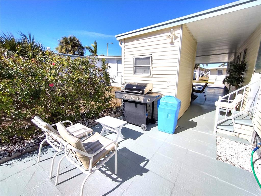 A patio area features a grill, a blue bin, and outdoor seating beside a mobile home — 82286 2ND AVENUE N UNIT 286, PINELLAS PARK, FL
