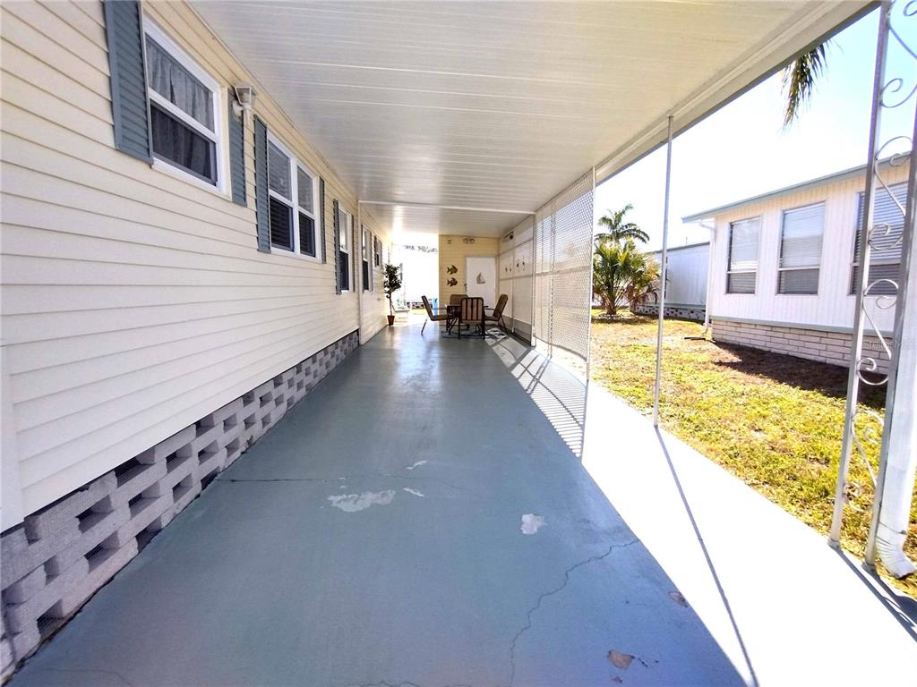 A long, covered concrete carport runs alongside a light-colored mobile home with lattice skirting — 82286 2ND AVENUE N UNIT 286, PINELLAS PARK, FL