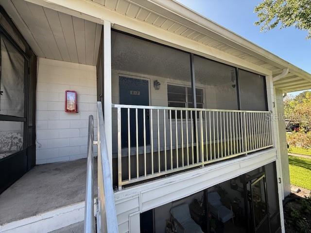 An exterior view shows a second-story screened balcony with a metal railing and stairs — 700 E AIRPORT BOULEVARD UNIT E7, SANFORD, FL