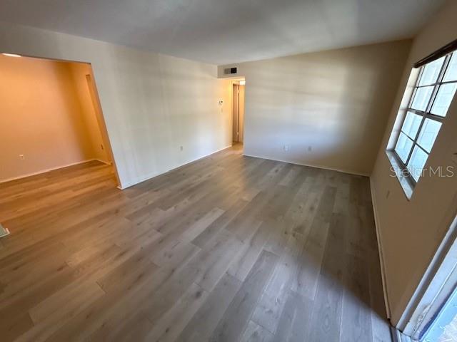 An empty room features light wood-look flooring, beige walls, and a large window — 700 E AIRPORT BOULEVARD UNIT E7, SANFORD, FL