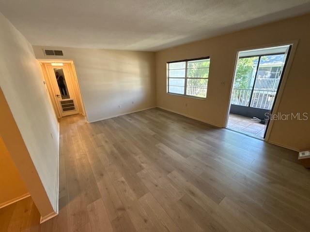 An empty room features light wood-look flooring, a window, and a sliding glass door — 700 E AIRPORT BOULEVARD UNIT E7, SANFORD, FL