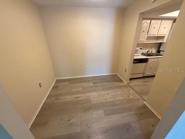 A dining area with light wood-look flooring leads into a kitchen with white cabinets — 700 E AIRPORT BOULEVARD UNIT E7, SANFORD, FL