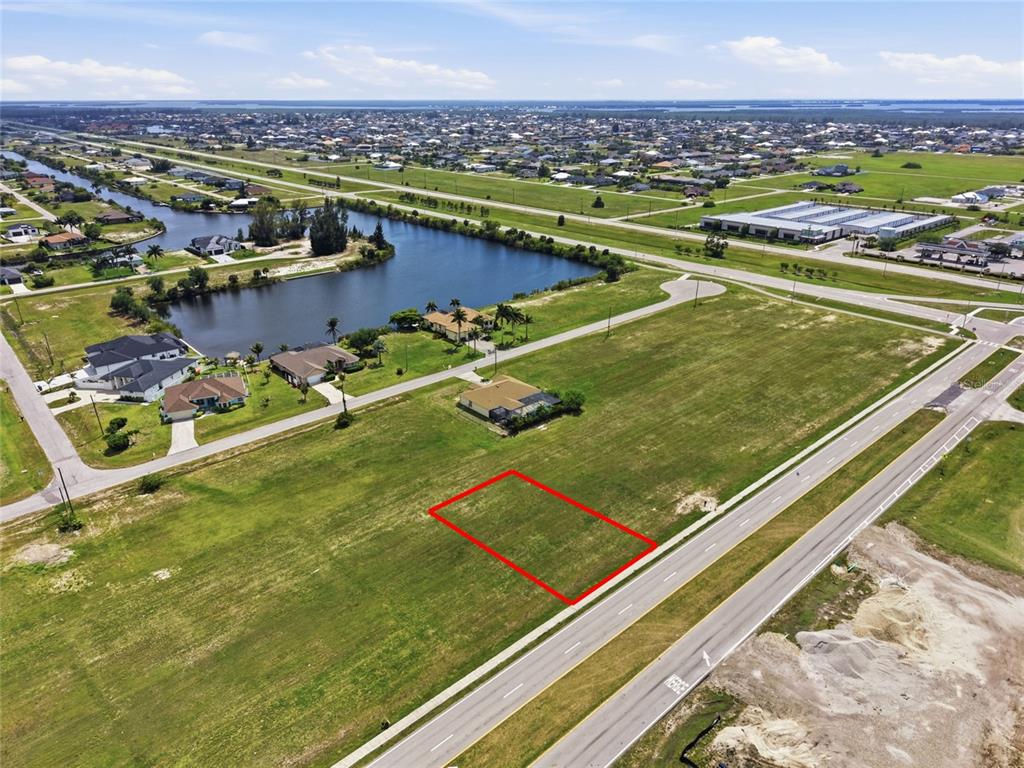 An aerial view shows a vacant rectangular lot outlined in red along a paved road — 3008 TROPICANA PARKWAY W, CAPE CORAL, FL