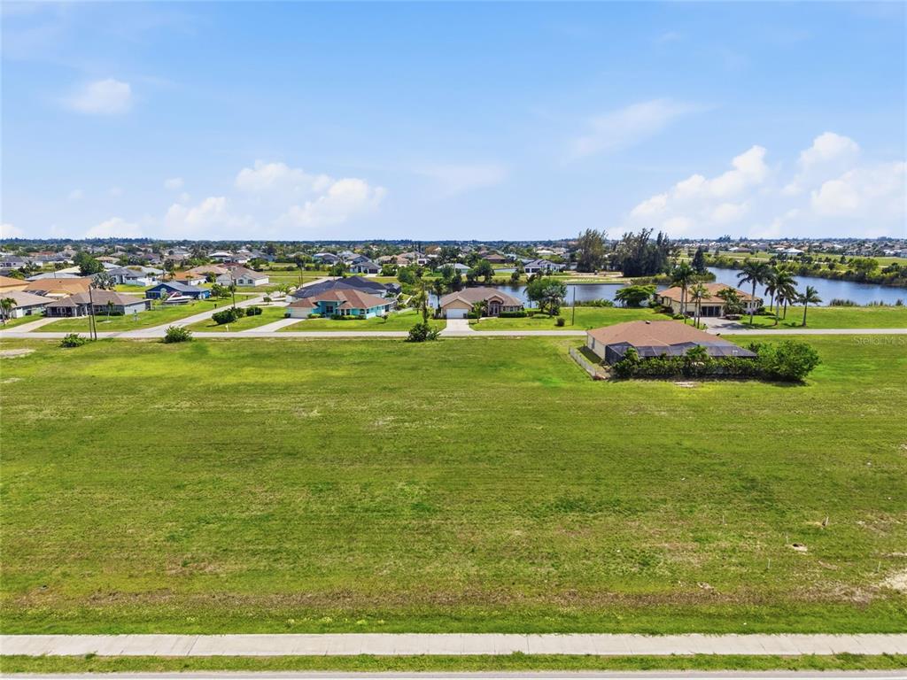 An aerial view shows a large, vacant grassy lot situated in a residential neighborhood — 3008 TROPICANA PARKWAY W, CAPE CORAL, FL