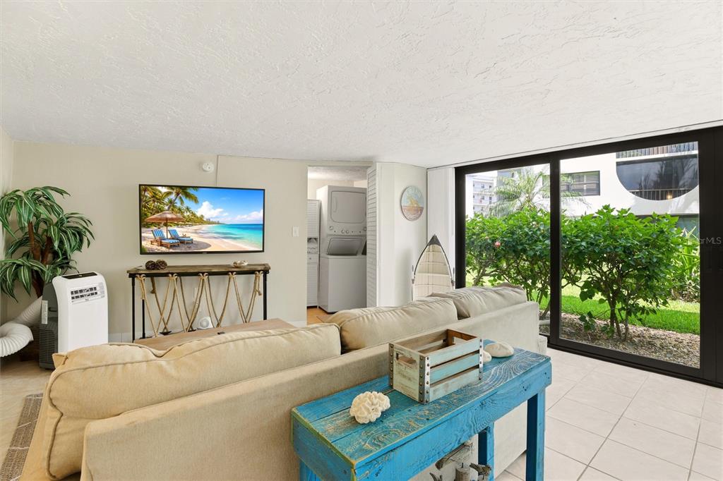 A living room features a beige sofa, a blue wooden console table, and a television — 1011 ANGLERS COVE UNIT H203, MARCO ISLAND, FL