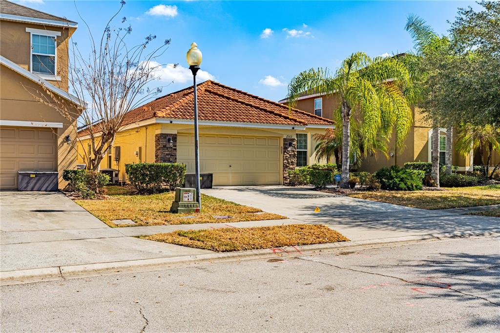 A single-story house with a tan stucco exterior, a tile roof, and a two-car garage — 2513 DHARMA CIRCLE, KISSIMMEE, FL