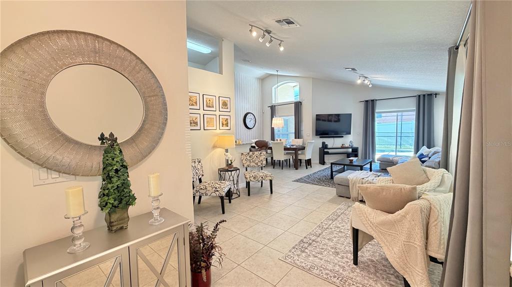 An open-concept living and dining area features tile flooring, neutral walls, and modern decor — 2513 DHARMA CIRCLE, KISSIMMEE, FL