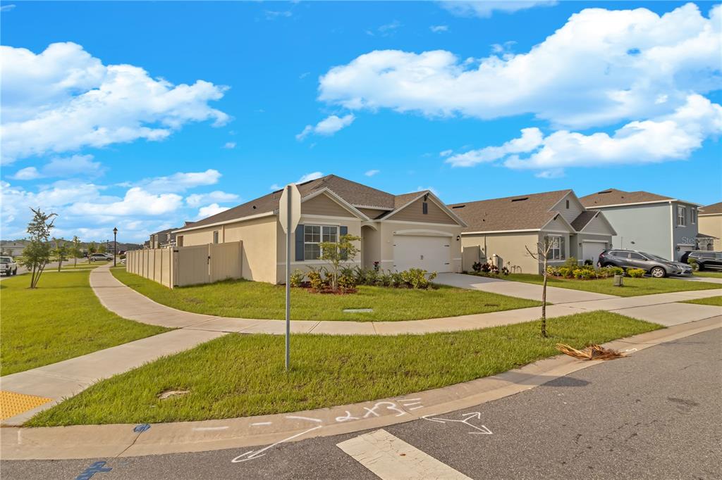 A single-story suburban house with a tan exterior, white garage, and a sidewalk in front — 452 NOBLE AVENUE, DAVENPORT, FL